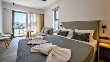 A hotel room with a large bed, a ceiling fan, a balcony with a view, and a seating area with chairs.