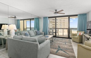 Relax in this stylish room with a large sofa, armchair, and sliding glass door leading to a balcony with a view.