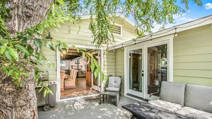 A patio with a table and chairs, a bench, and a sliding glass door leading to an interior space. - 316MAR - Modern Avalon house, AC, WIFI, Golf Cart and patio with BBQ (Avalon)