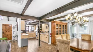 A spacious kitchen with wooden cabinets, a dining area with a large table and upholstered chairs, and a chandelier. - 316MAR - Modern Avalon house, AC, WIFI, Golf Cart and patio with BBQ (Avalon)