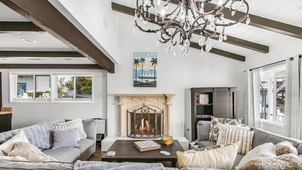 A spacious living room with a fireplace, two sofas, a coffee table, and a chandelier. - 316MAR - Modern Avalon house, AC, WIFI, Golf Cart and patio with BBQ (Avalon)