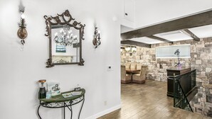 A foyer with a wooden floor, a stone wall, a chandelier, and a staircase with a stone railing. - 316MAR - Modern Avalon house, AC, WIFI, Golf Cart and patio with BBQ (Avalon)