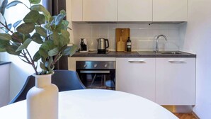 Una cocina moderna con armarios blancos, un lavamanos de acero inoxidable, una cafetera, un tostador y un bloque de cuchillos.
