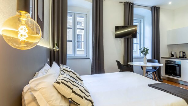 Una habitación de hotel con una cama, un escritorio, una silla, un televisor y una ventana.
