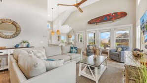 A spacious living room with a high ceiling fan, a large mirror, and a skateboard mounted on the wall. - Semi-Oceanfront Home w/ Private Pool, Tiki Bar, Hot Tub (Salvo)