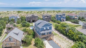 A coastal residential area with multiple houses, including a prominent blue house with a balcony and a wooden deck. - Semi-Oceanfront Home w/ Private Pool, Tiki Bar, Hot Tub (Salvo)