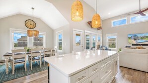 A spacious kitchen with a large island, pendant lights, and a dining area with chairs and a table. - Semi-Oceanfront Home w/ Private Pool, Tiki Bar, Hot Tub (Salvo)