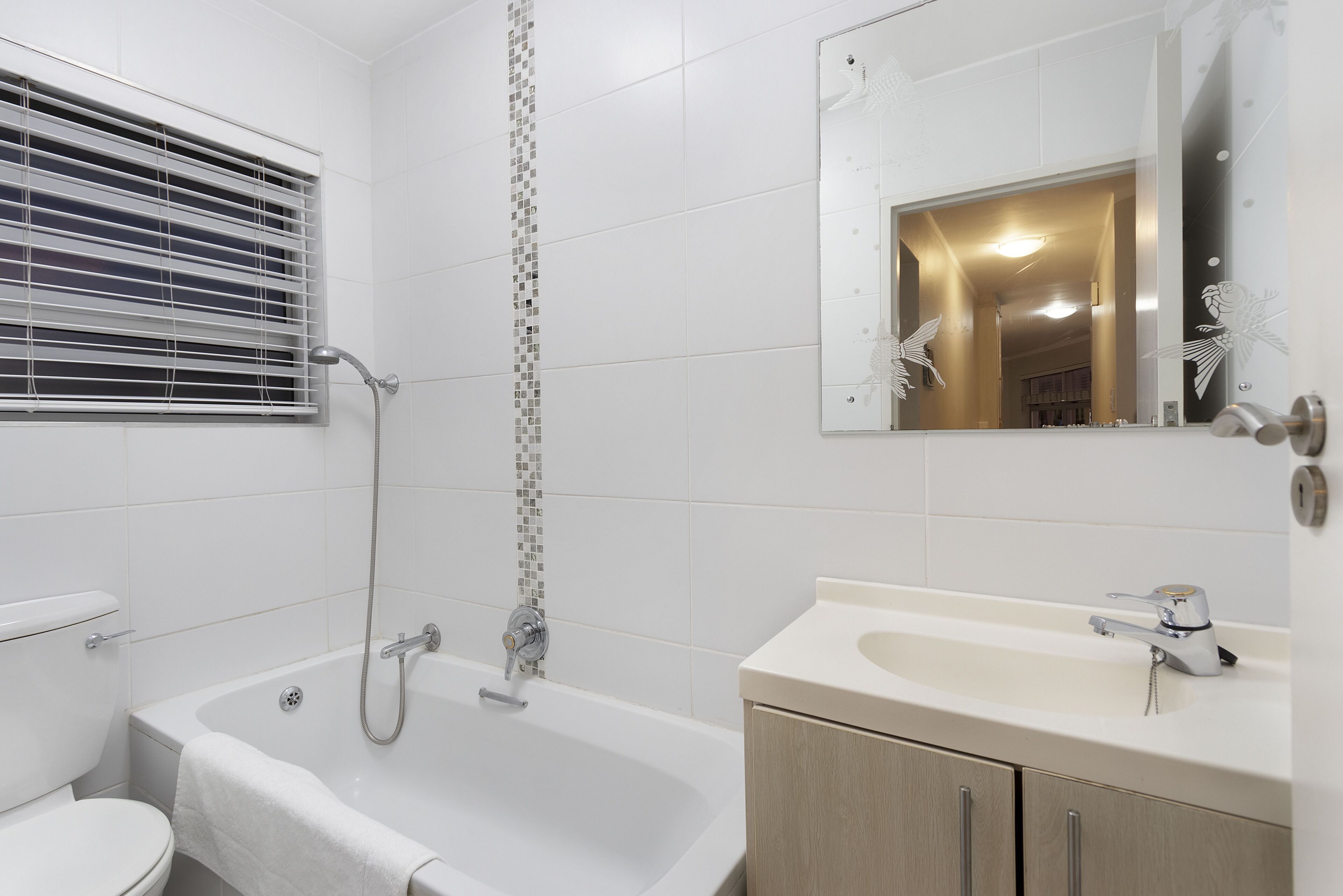 A bathroom with a bathtub, toilet, sink, and a mirror.