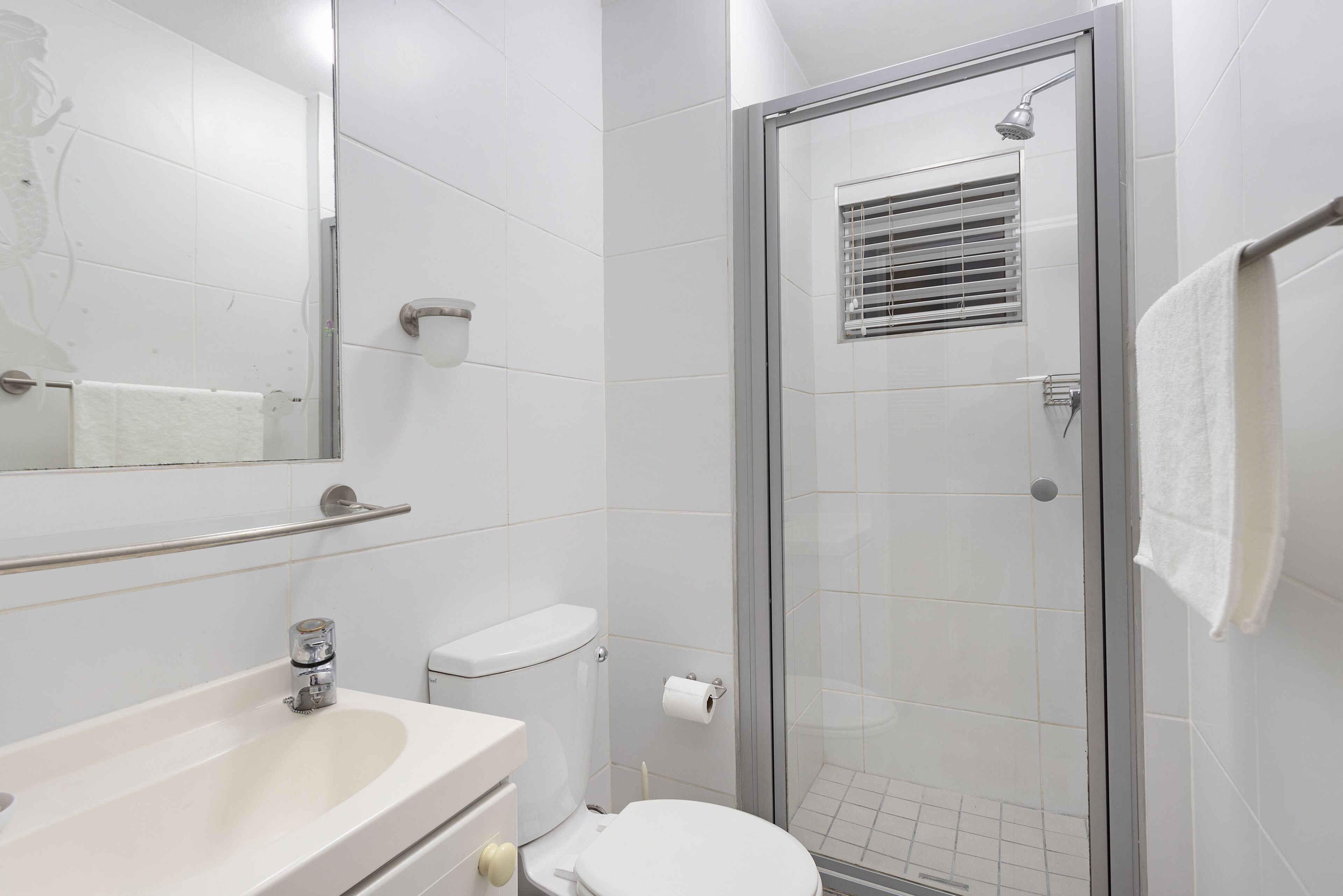 Un baño moderno con cabina de ducha de vidrio, un lavamanos blanco y un inodoro.