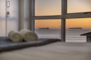 Une vue à travers une fenêtre d’un navire sur l’eau, au coucher du soleil.