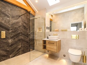 A modern bathroom with a glass-enclosed shower, a wooden vanity, and a large mirror.