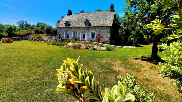 Una casa de piedra con un césped cuidado y un jardín al frente.