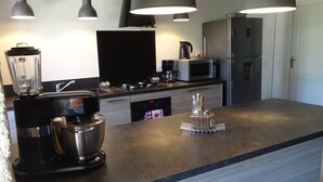 Una cocina moderna con batidora integrada, cafetera, microondas y refrigerador.