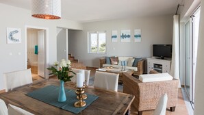 A spacious living area with a dining table, wicker furniture, and a television. - Villa Melodie, fantastic pool & terraces, sea view (Vamos)