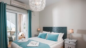 A hotel room with a bed, a nightstand, a lamp, a ceiling fan, and a view of the outside. - Villa Melodie, fantastic pool & terraces, sea view (Vamos)