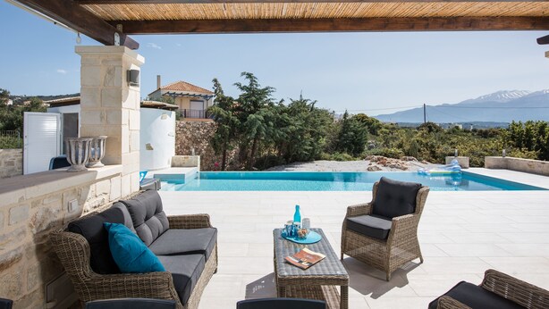 A covered outdoor area with a pool, wicker furniture, and stone architecture. - Villa Melodie, fantastic pool & terraces, sea view (Vamos)