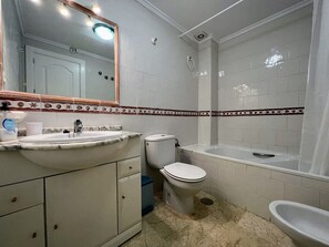 A bathroom with a sink, toilet, bathtub, and a mirror.