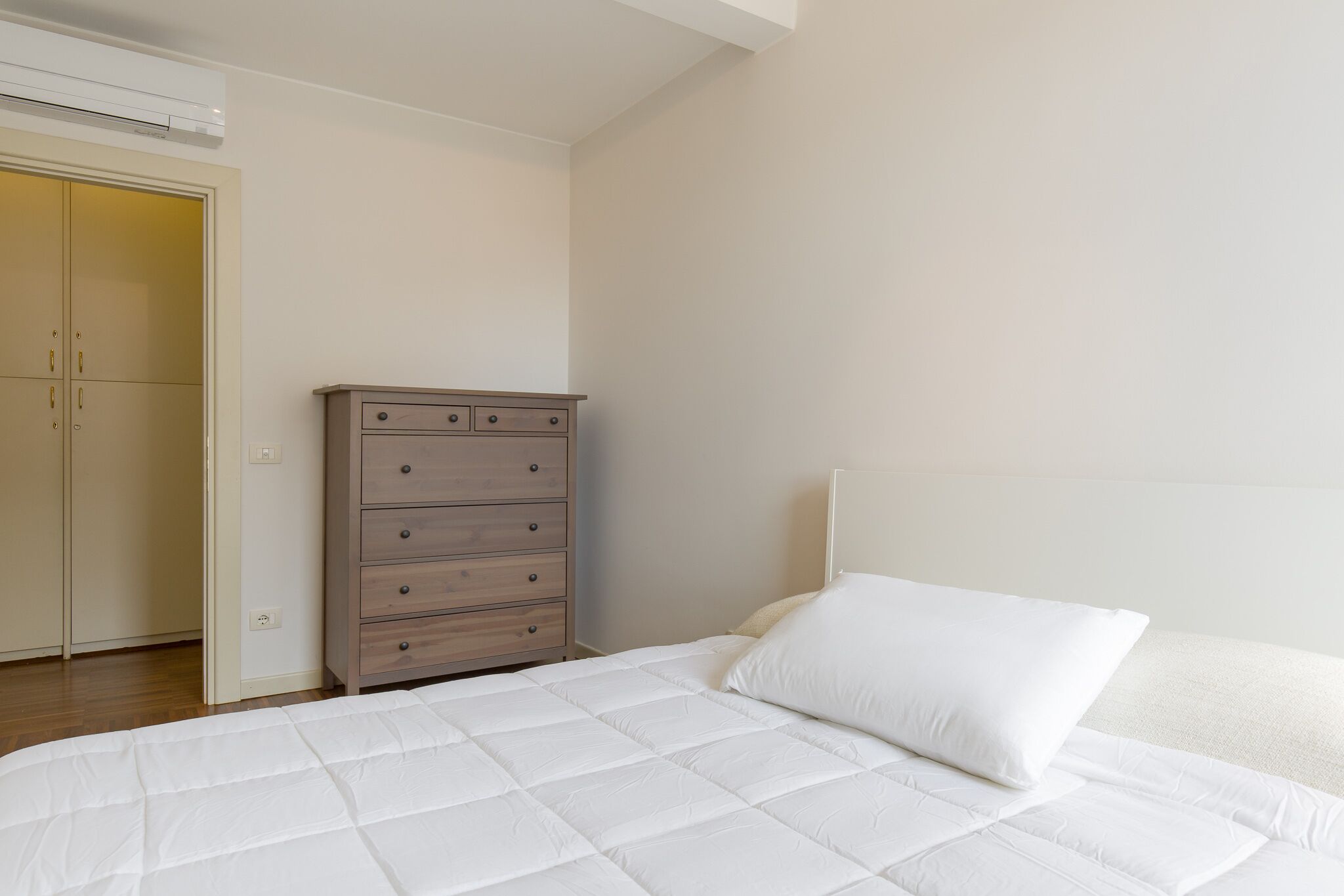 A bedroom with a bed, a dresser, and a wardrobe.