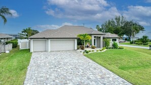 A residential house with a paved driveway, garage, and a well-maintained lawn.