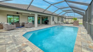 An indoor swimming pool with a covered patio area, furnished seating, and a view of the surrounding landscape.