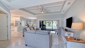 A spacious living area with a grey sofa, a TV, and a lamp on a wooden side table.