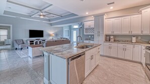 A spacious kitchen with white cabinets, a marble countertop, and a built-in dishwasher.