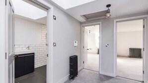 Un intérieur moderne comprenant une cuisine, un radiateur et un couloir menant à une autre pièce.