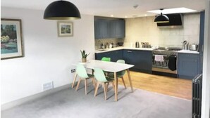 Une cuisine moderne avec un coin repas, comprenant une table ronde et des chaises, une cuisinière et des placards.