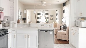 A modern kitchen with white cabinetry, a central island, and a dining area with a sofa and table.