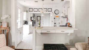 A modern kitchen with white cabinetry, pendant lighting, and a central island.