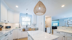A modern kitchen with white cabinetry, a large marble island, and a unique woven pendant light. - Beach Blessing - Southern Shores, 225 to Beach Access, Quiet Area, Hot Tub, Pets OK, Flex Stays (Southern Shores)