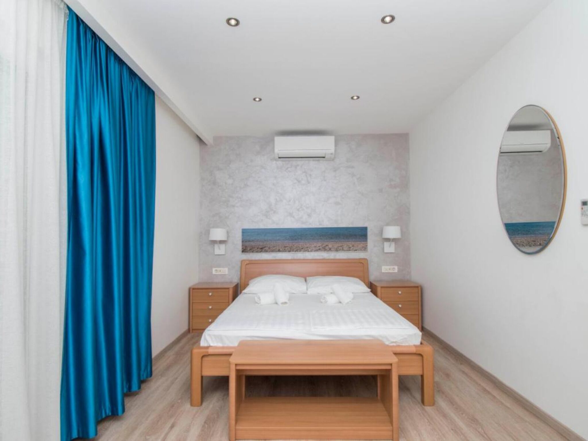 Un dormitorio con cama, mesitas de noche, un espejo y un aire acondicionado de pared.