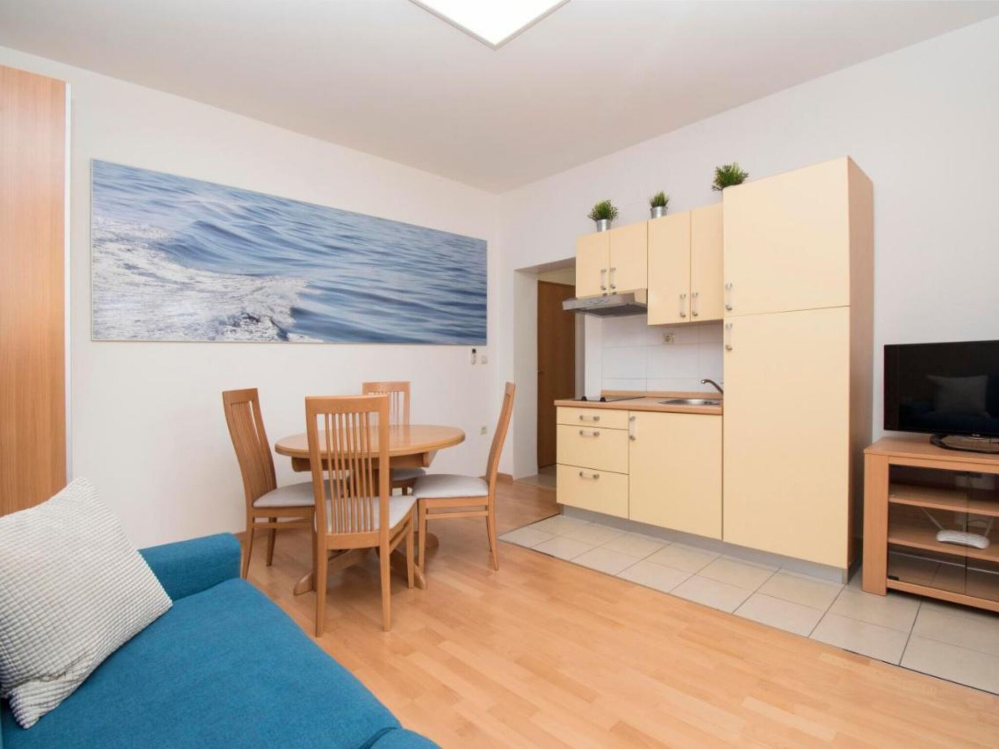 Een knus woongedeelte met een eethoek, kitchenette en een televisie.