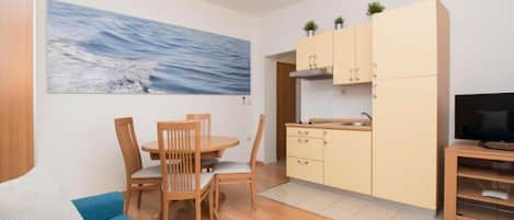 Een knus woongedeelte met een eethoek, kitchenette en een televisie.