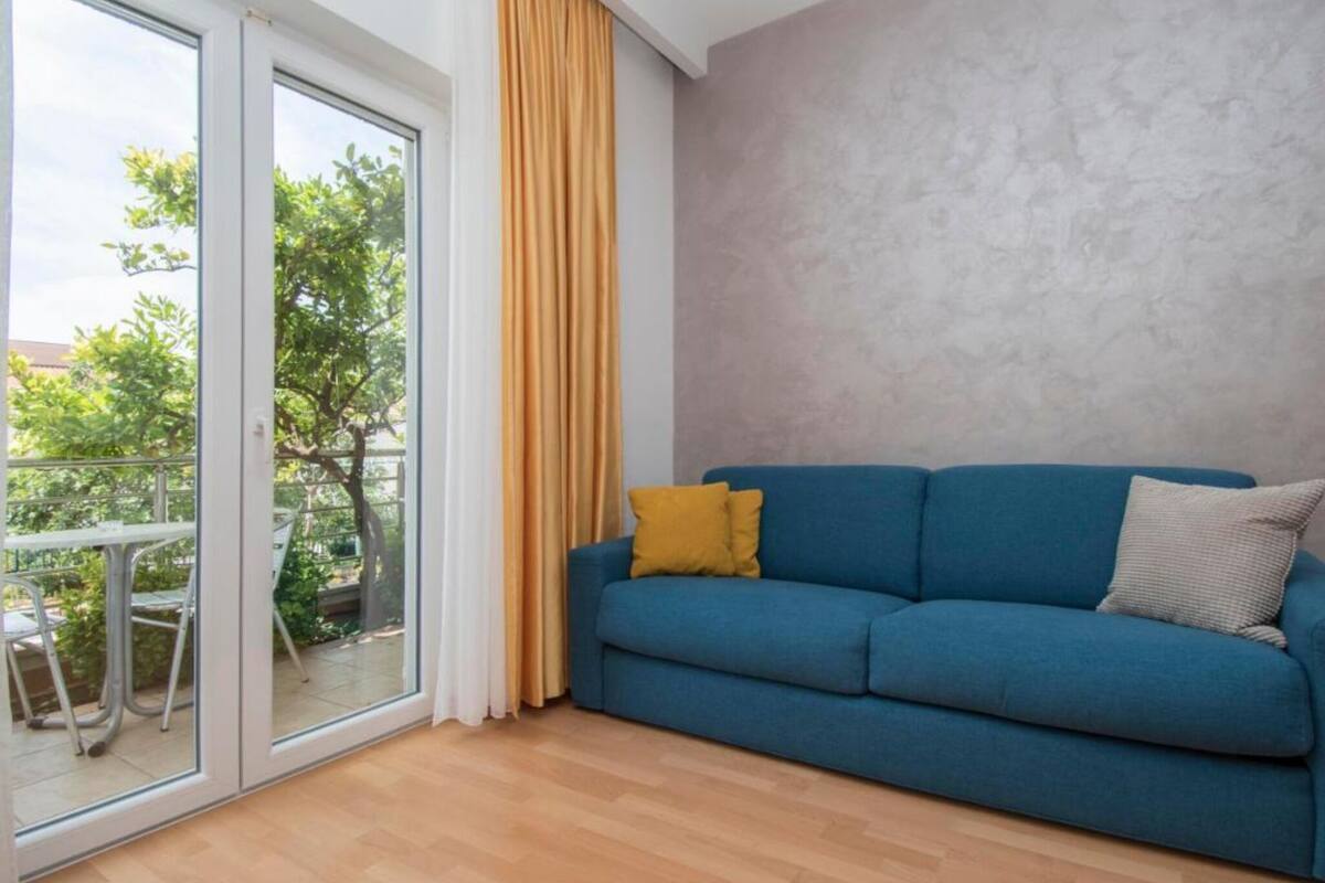 A room with a blue sofa, a yellow pillow, and a grey wall.