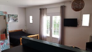 Une chambre avec deux lits, une télévision, une table et une fenêtre avec des rideaux.