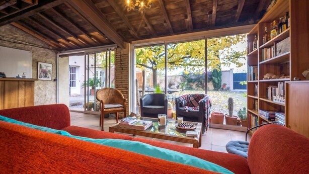 Un salon chaleureux avec un canapé rouge, une table basse et une bibliothèque.