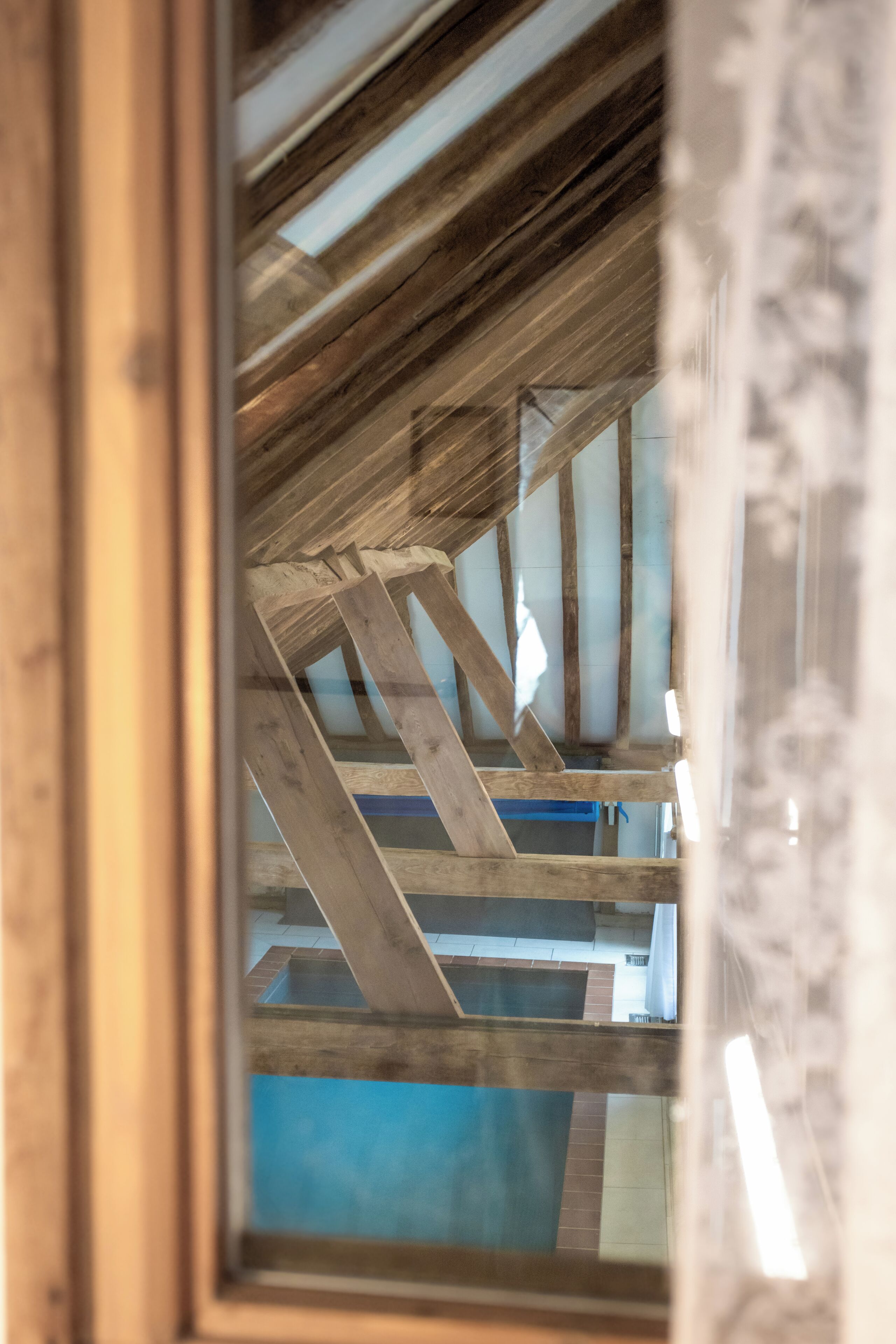 A wooden ceiling structure with visible beams and a blue wall below.
