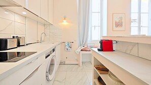 A modern kitchen with a built-in washing machine, a sink, and a coffee machine. - Viva Riviera Studio 5 Rue Florian (Cannes)