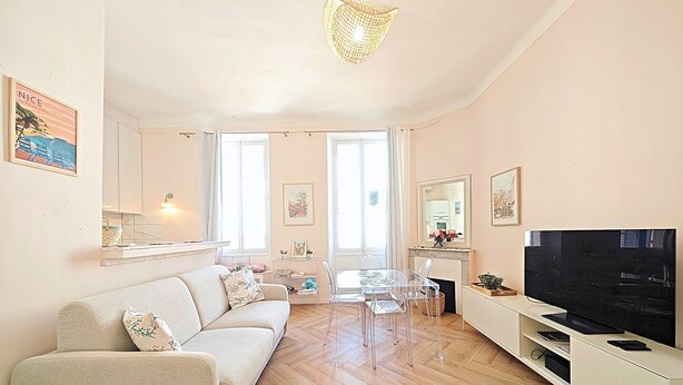 A living room with a sofa, a TV, a dining table with chairs, and a fireplace. - Viva Riviera Studio 5 Rue Florian (Cannes)