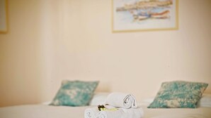 A neatly made bed with two pillows, a rolled towel, and two bottles of lotion on the bed. - Viva Riviera Studio 5 Rue Florian (Cannes)