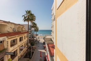 Ein Hotel mit Blick auf den Strand, Palmen und einen klaren Himmel.