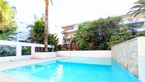 Une piscine avec un mur en pierre et un palmier.