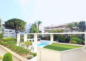 A rooftop with a swimming pool, green lawn, and surrounding trees.
