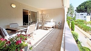 Un balcon avec des meubles d’extérieur, une vue sur la rue et un immeuble en arrière-plan.