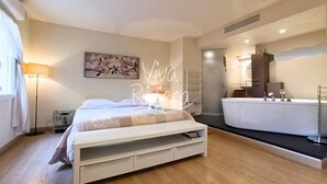 Une chambre à coucher moderne avec un lit, une table de chevet, une lampe et une grande fenêtre.