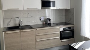 Eine moderne Küche mit weißen Schränken, einer schwarzen Arbeitsplatte und einem eingebauten Backofen.