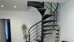 Ein modernes Wohnzimmer mit Wendeltreppe, einem Ledersofa und Holzboden.
