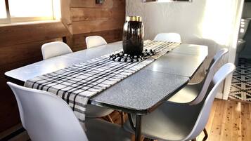 A dining table with a checkered table runner, white chairs, and a decorative centerpiece.