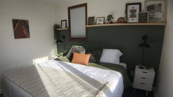 A neatly arranged bedroom with a bed, bedside table, lamp, and wall decorations.